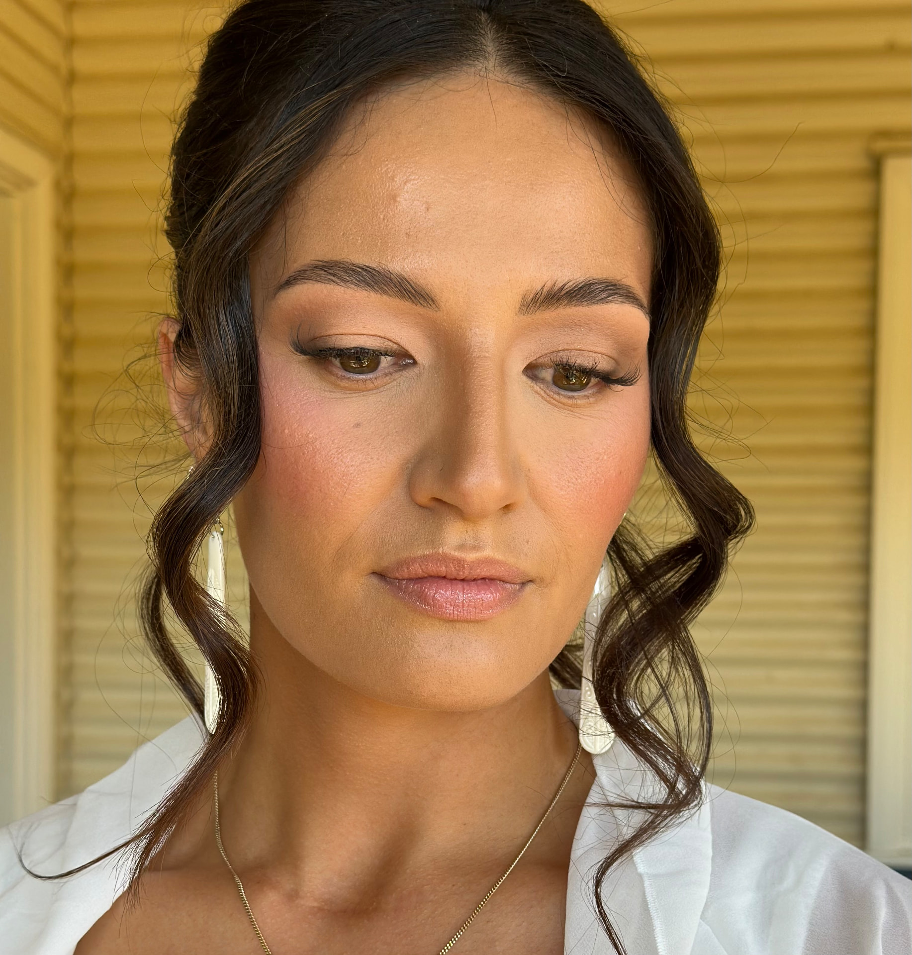 Brunette bride with soft face-framing waves and radiant skin-like makeup