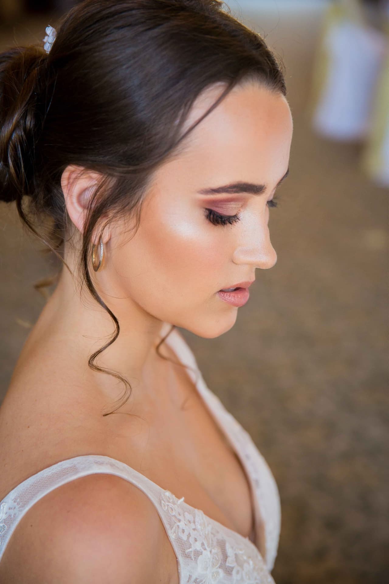 Profile of a real bride with a glowing skin-like base, soft smoky eye and a brunette updo with tendrils