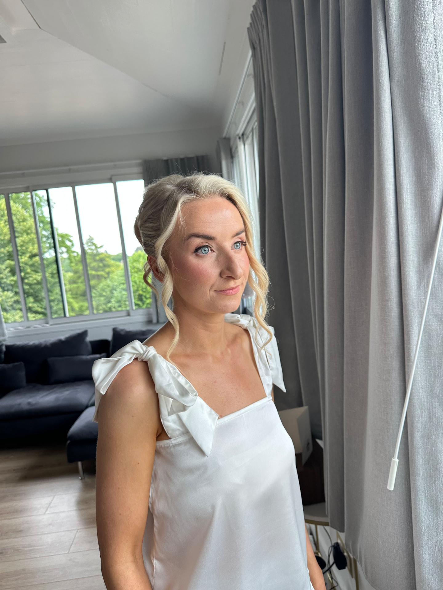 Real bride in a white silk slip with a soft blonde updo and natural glowing makeup