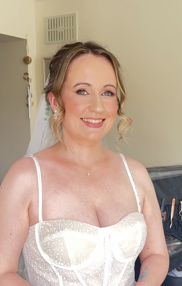 Suzanne after her bridal soft glam makeup — warm even base, soft blush, defined eyes and a rose lip, finished with her veil and gown