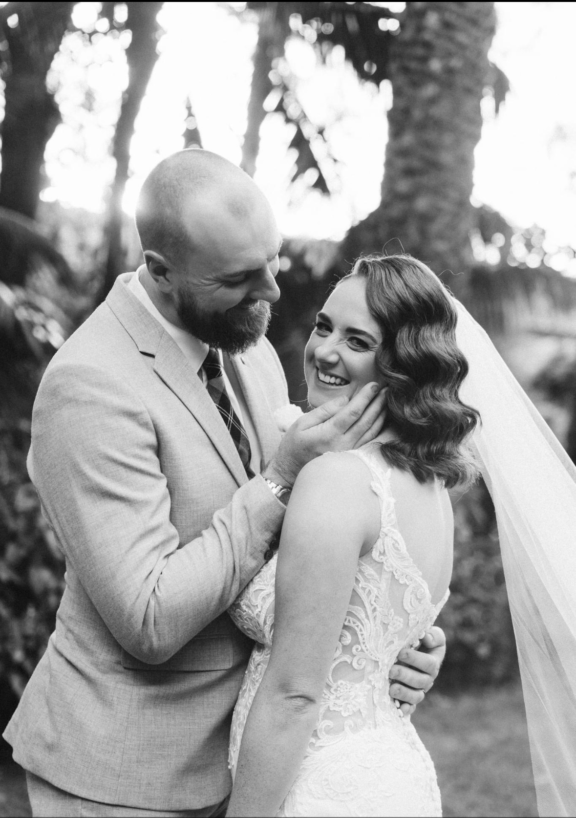 Black and white portrait of a real bride with vintage finger waves and a veil, laughing with her groom