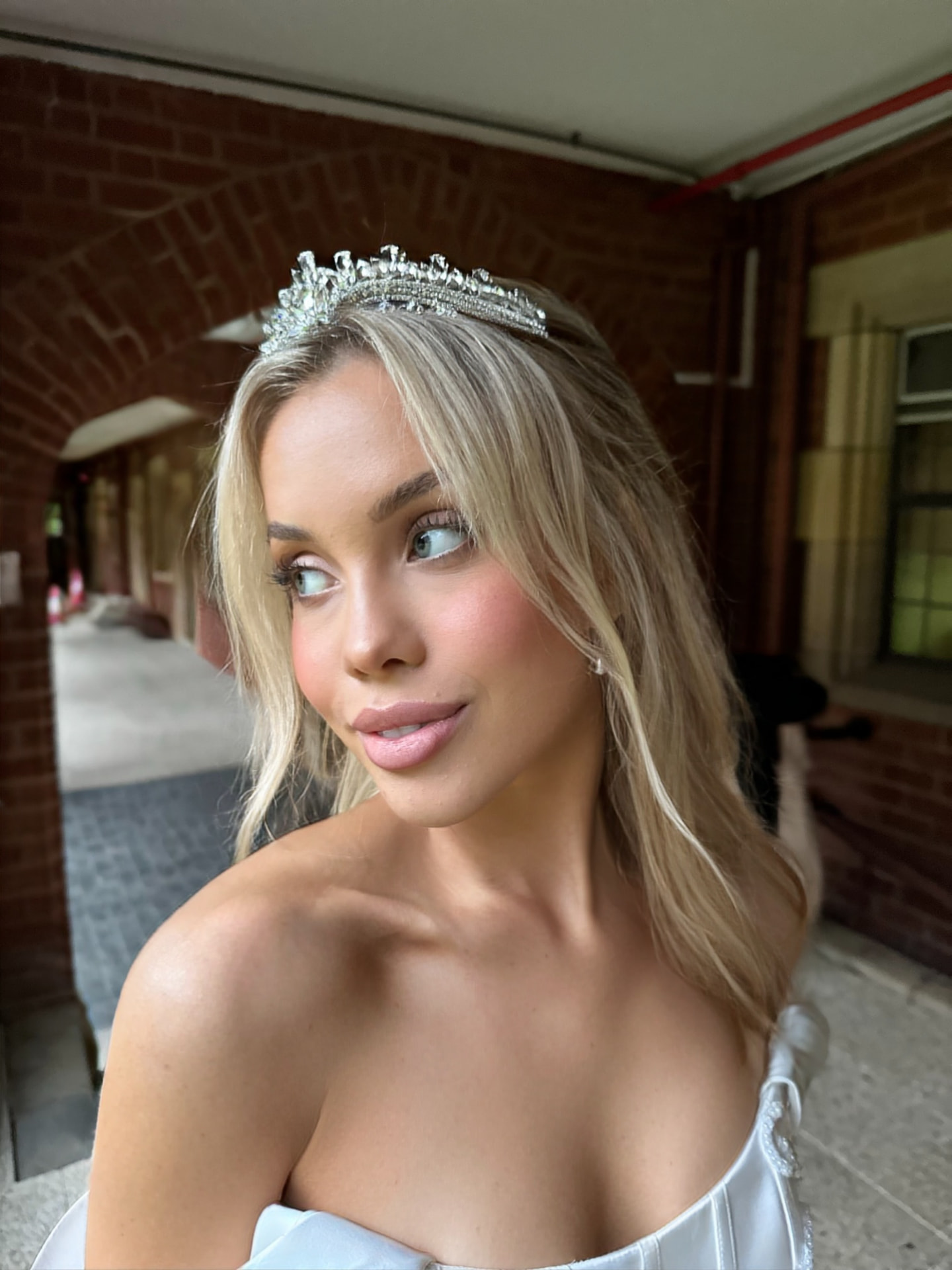 Blonde bride in a crystal tiara with soft waves and fresh luminous makeup