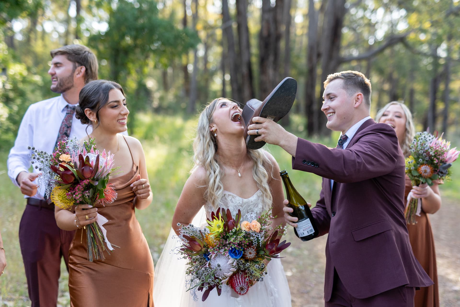 Real bride laughing with her bridal party outdoors, long blonde waves and long-wear makeup