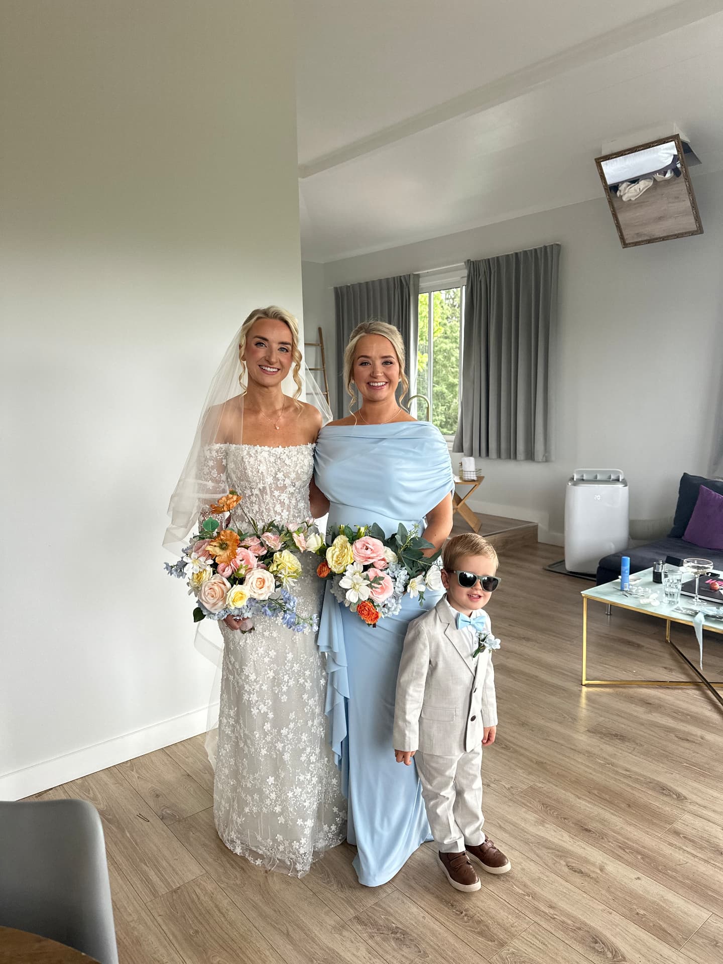 Real bride with her bridesmaid and page boy, both wearing polished soft glam makeup and bridal hair