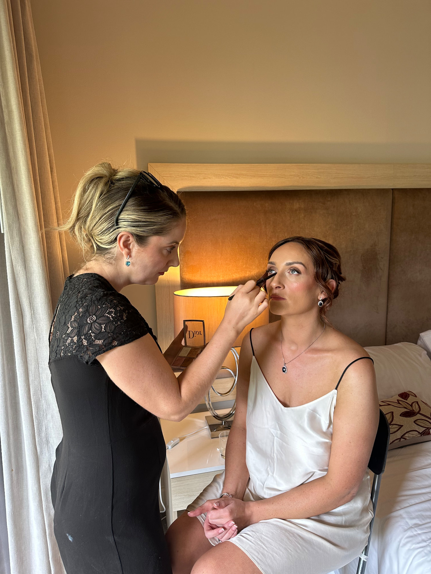 Evelyn applying soft bridal eye makeup with a brush on the wedding morning