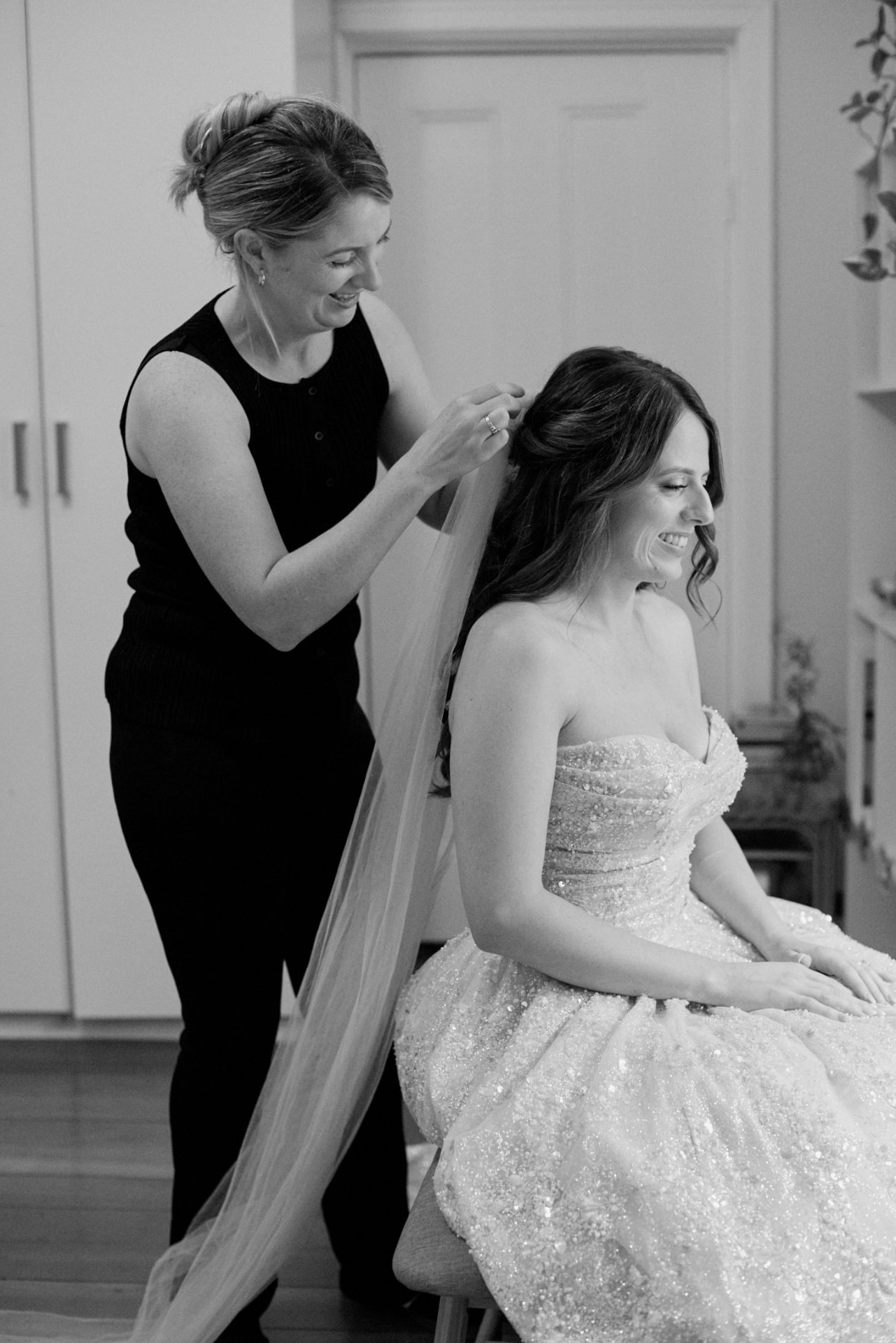 Evelyn placing a bride's cathedral veil on the morning of her wedding, black and white