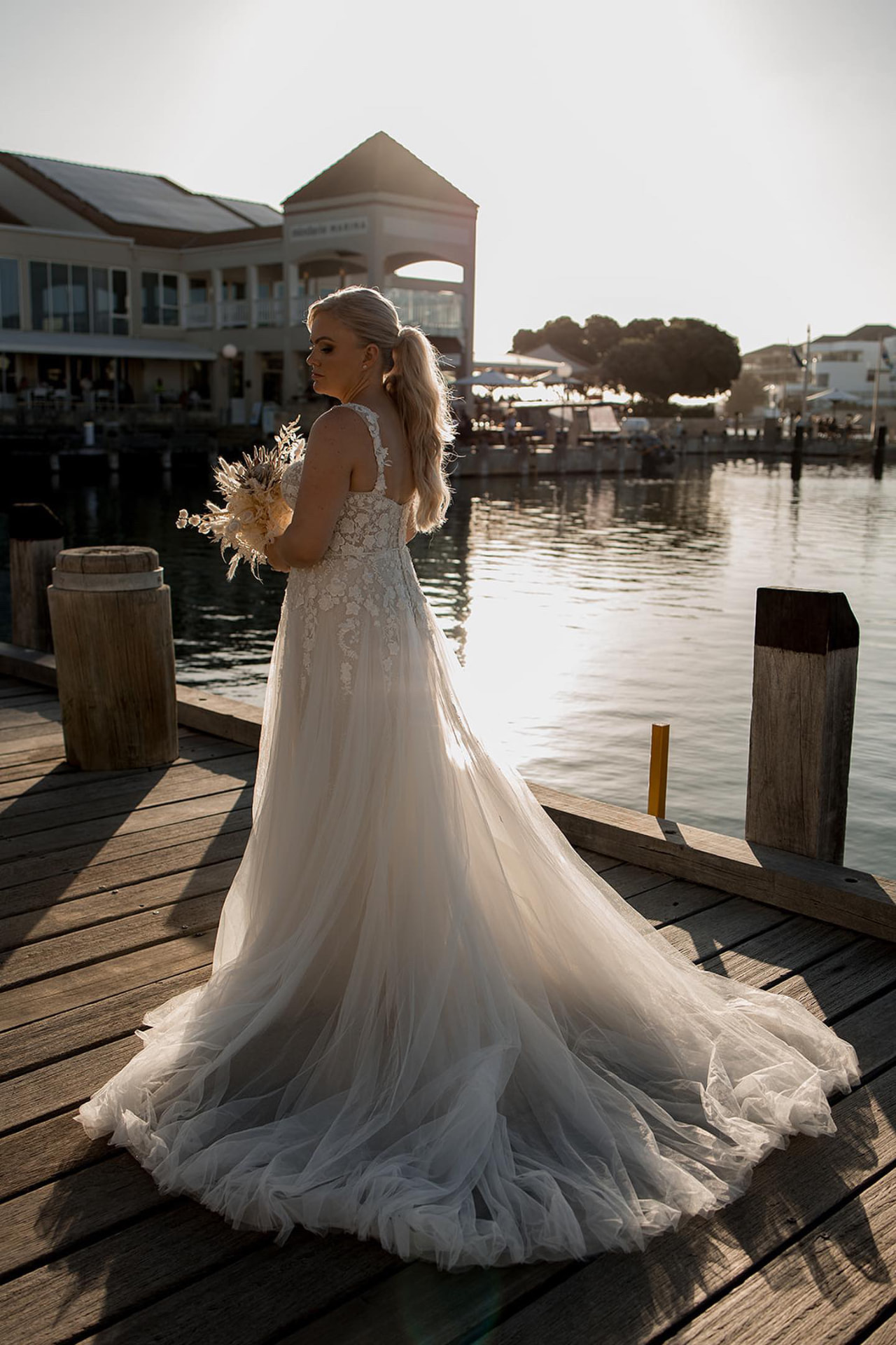 Real bride at the marina at golden hour with a textured blonde bridal ponytail and lace tulle gown