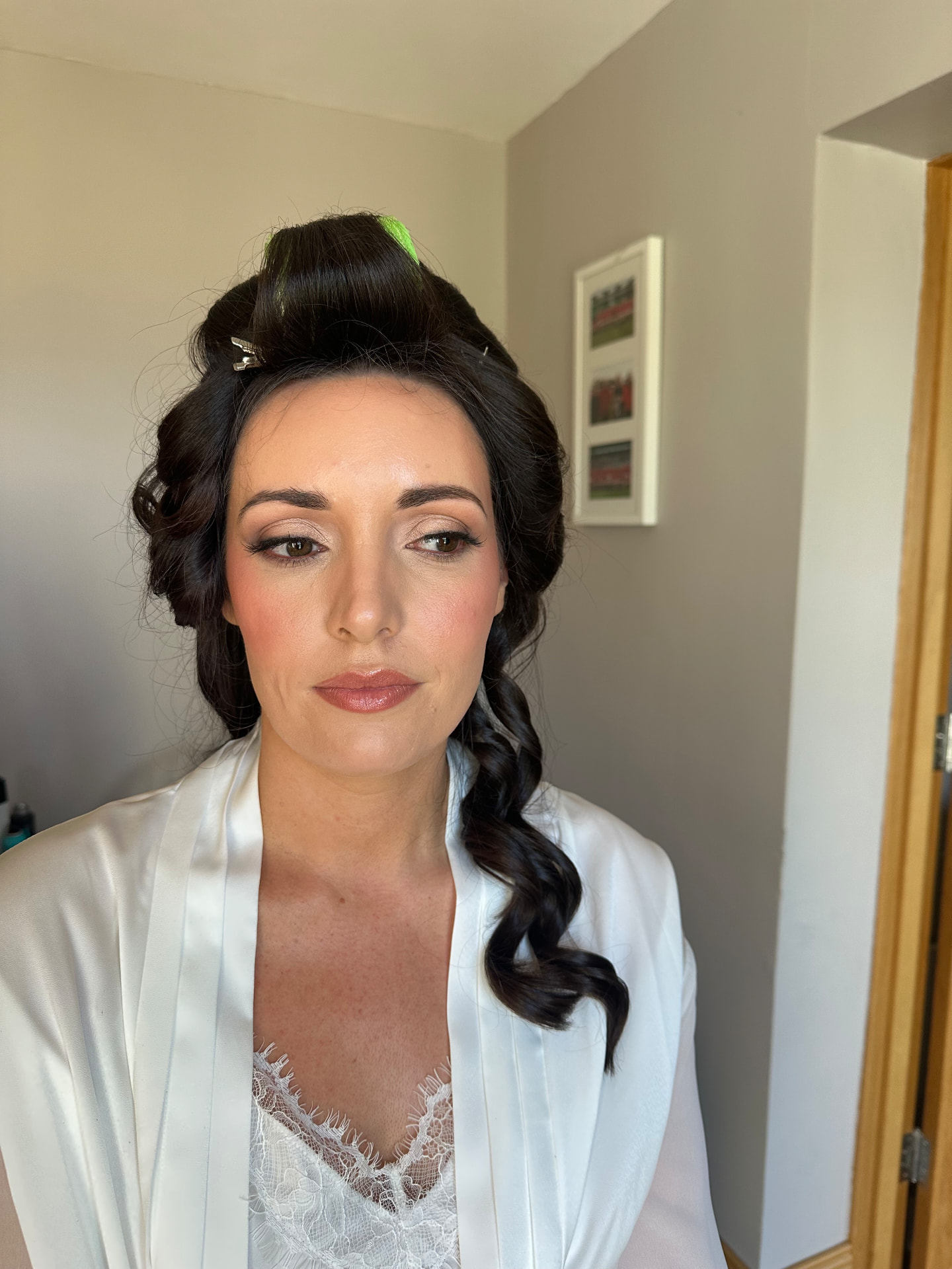 Real bride with a brunette half-up style and soft glam makeup in a white bridal robe