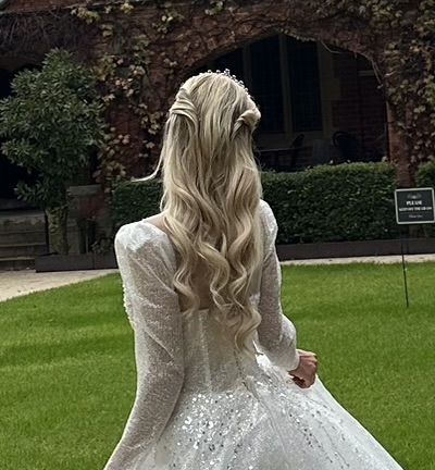 Real bride from behind in a sequinned gown with a blonde half-up style, soft waves and a delicate tiara